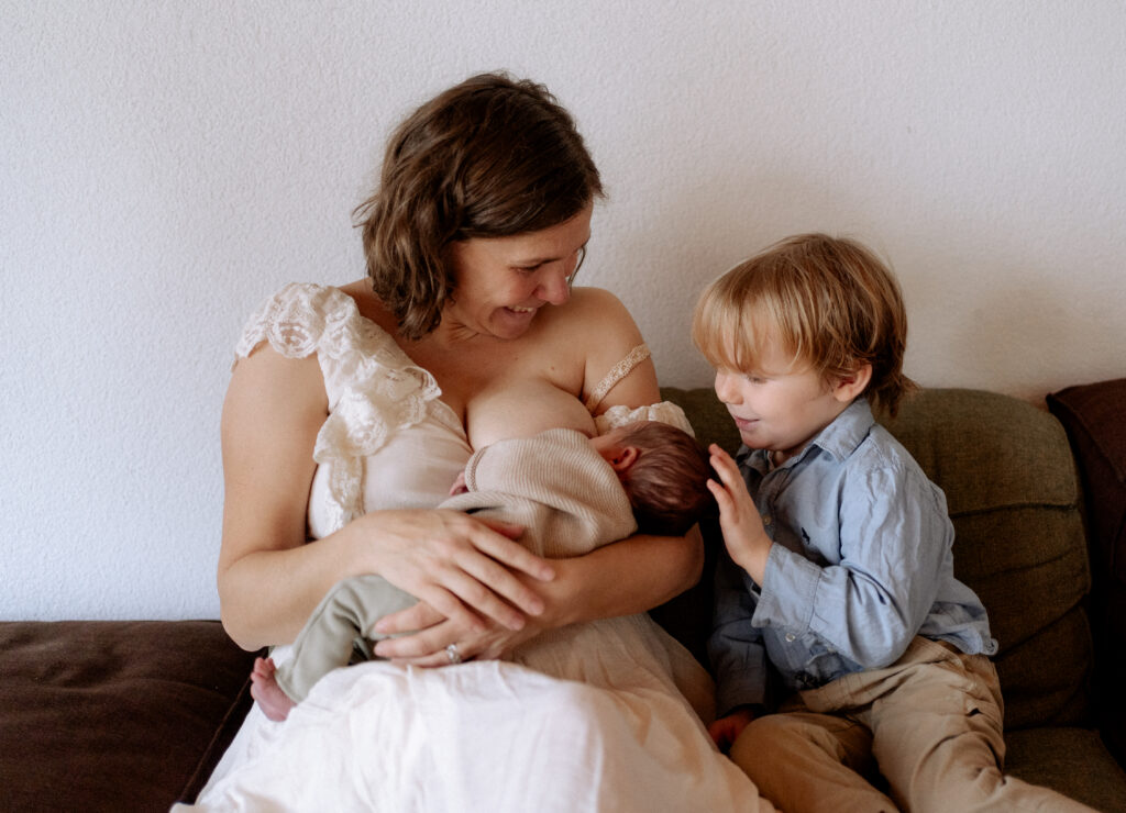 Geschwister kuschelt mit dem neugeborenen Baby