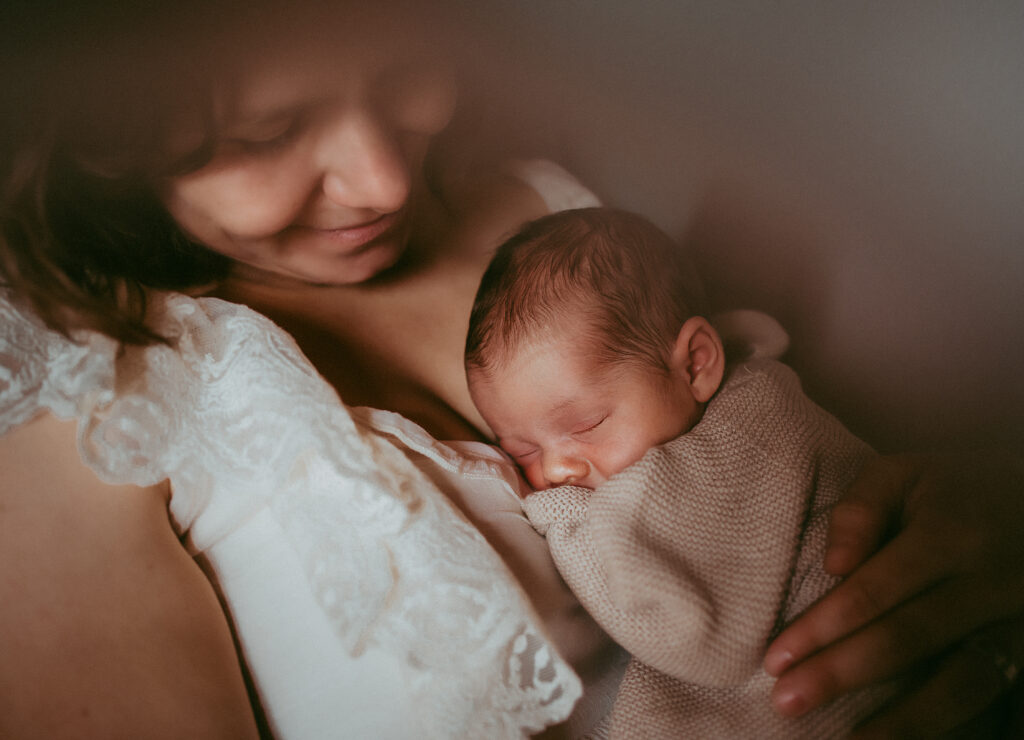 Baby eingekuschelt auf Mamas Brust beim Neugeborenenshooting